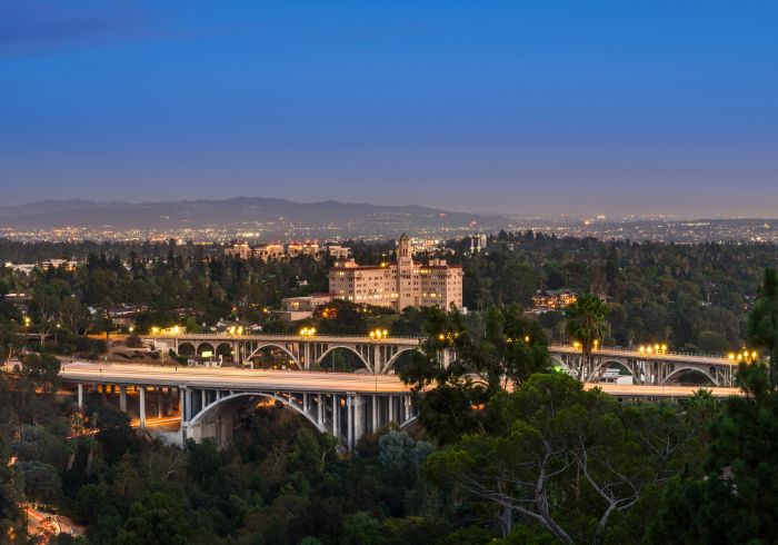 The Pasadena skyline at dusk with bridges, homes, and mountains in the distance