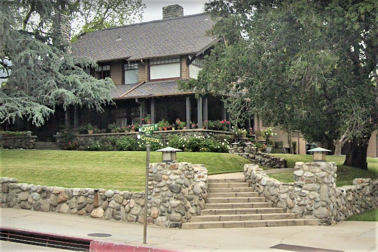 two story home with large windows, surrounded by trees. there is a stone wall and stairs leading from the sidewalk